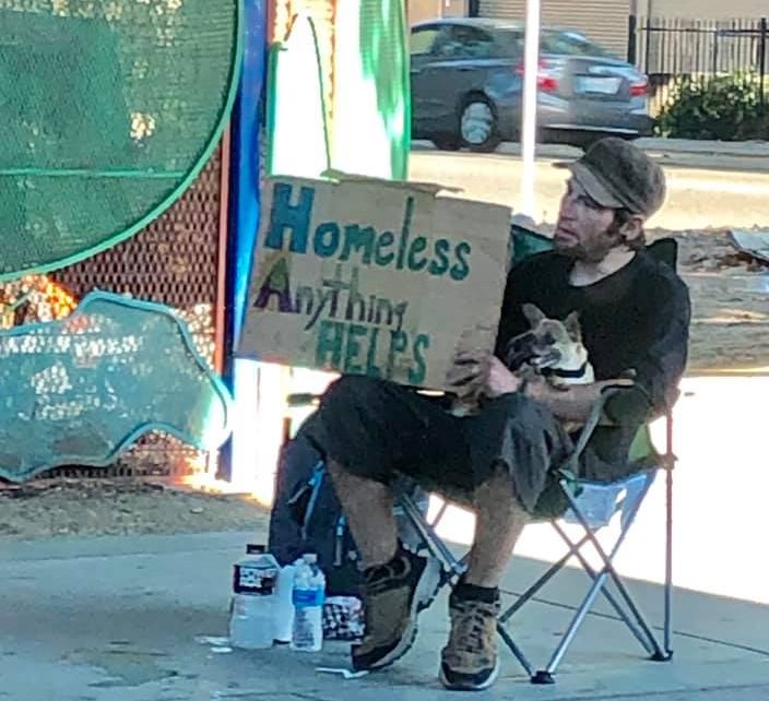 Homeless man with sign reading "Homeless Anything Helps"